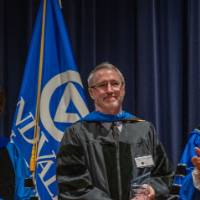 Provost and President applaud with man on stage